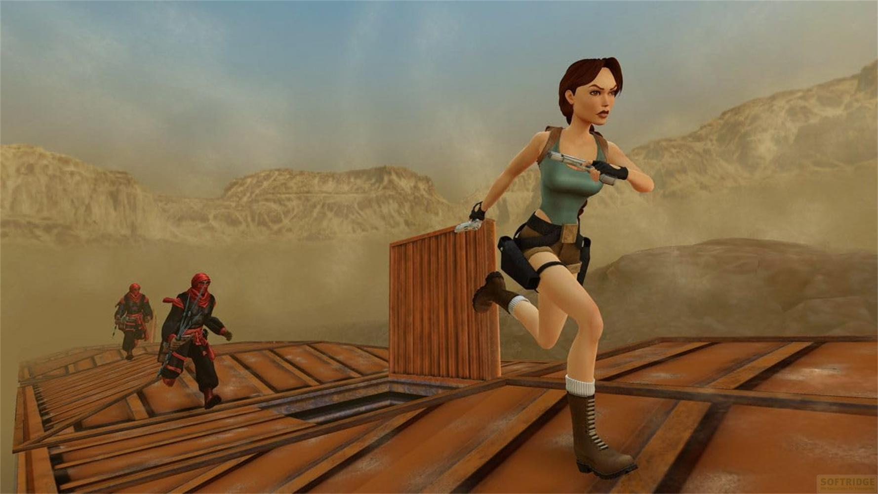 Lara Croft rennt auf einer Holzplattform, zwei Feinde verfolgen sie in der Wüste.