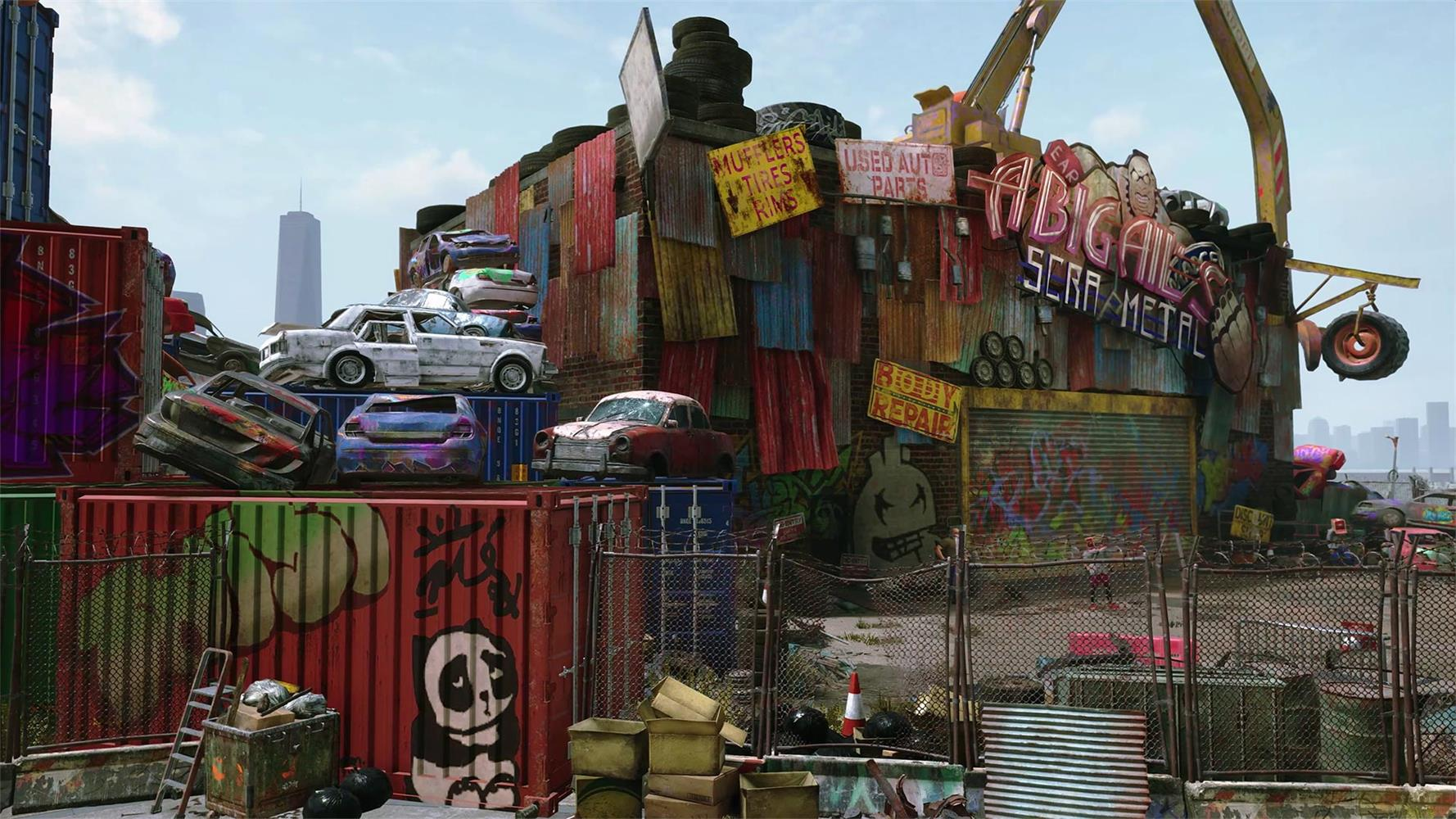 Schrottplatz mit Autos auf Containern und Reklameschildern. Ein Kran hängt ein Rad.