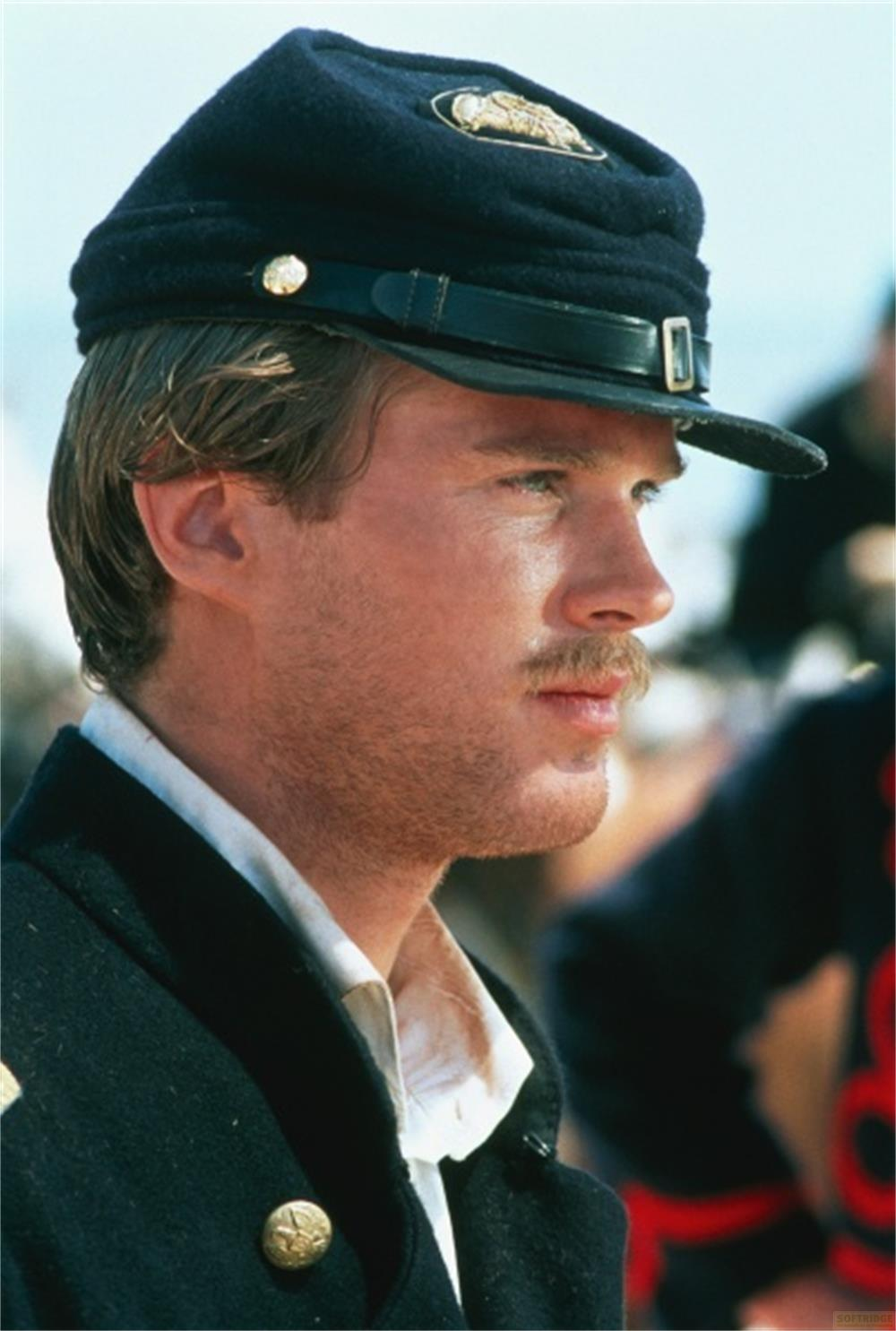 Un homme en uniforme, casquette et moustache regarde sur le côté.