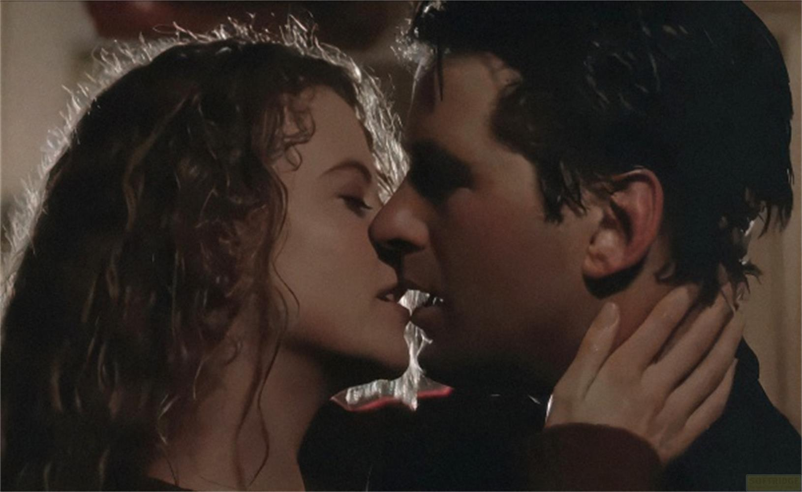 Primo piano di un uomo e una donna che si baciano. La donna ha i capelli ricci.
