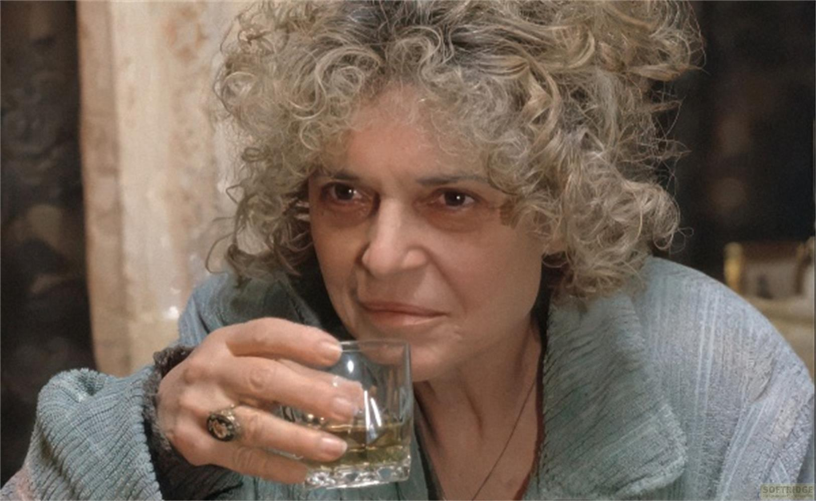 Una donna con capelli ricci beve da un bicchiere.