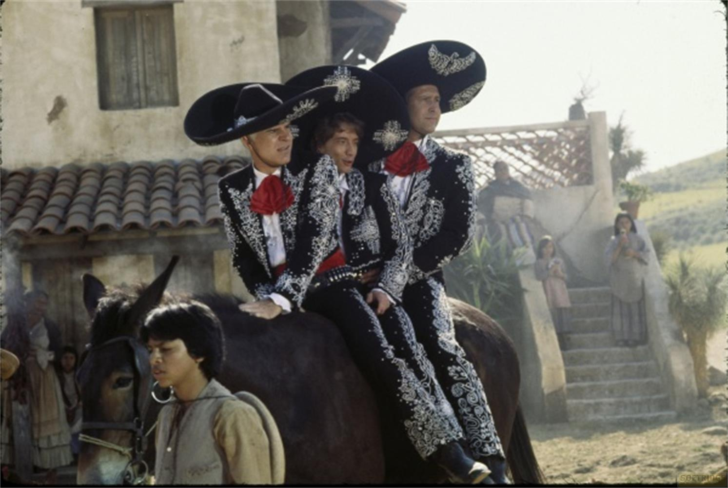 Tre uomini in abito da mariachi cavalcano un cavallo. Un ragazzo sta davanti.