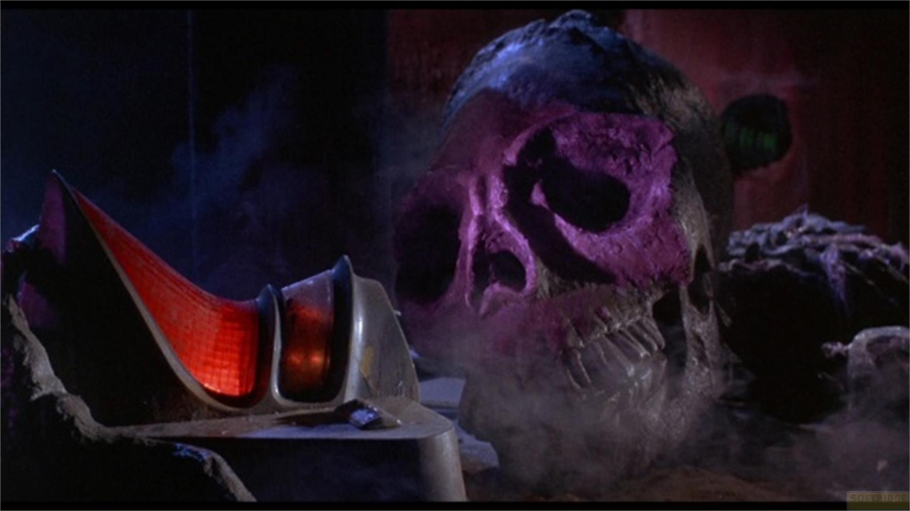 Un grande oggetto teschio viola accanto a un dispositivo rosso luminoso.