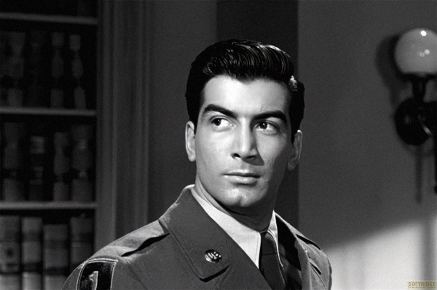 Un uomo in uniforme guarda a sinistra, con una libreria sullo sfondo.
