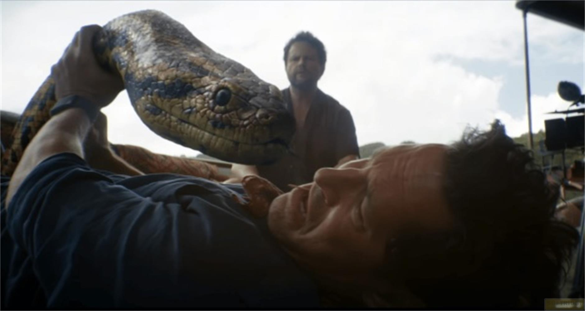 Un uomo tiene un grosso serpente mentre un altro uomo guarda sullo sfondo.