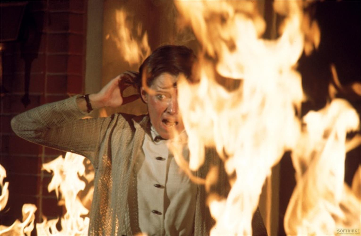 Una donna con espressione di panico tra le fiamme.
