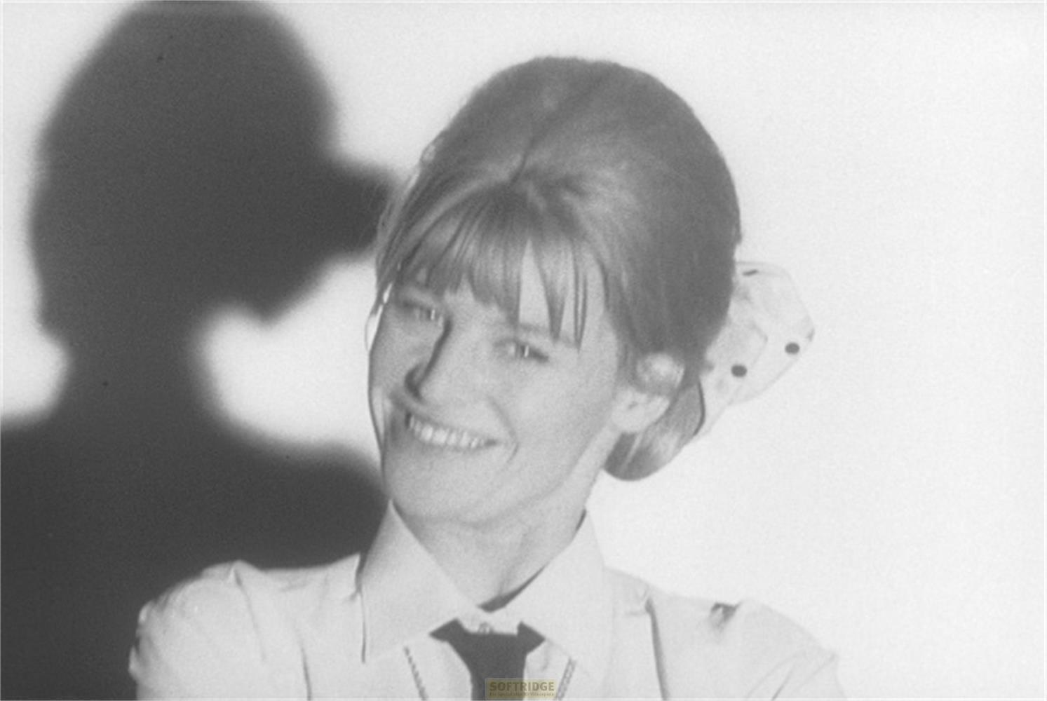 Donna sorridente, ombra dietro, chignon con fiocco.