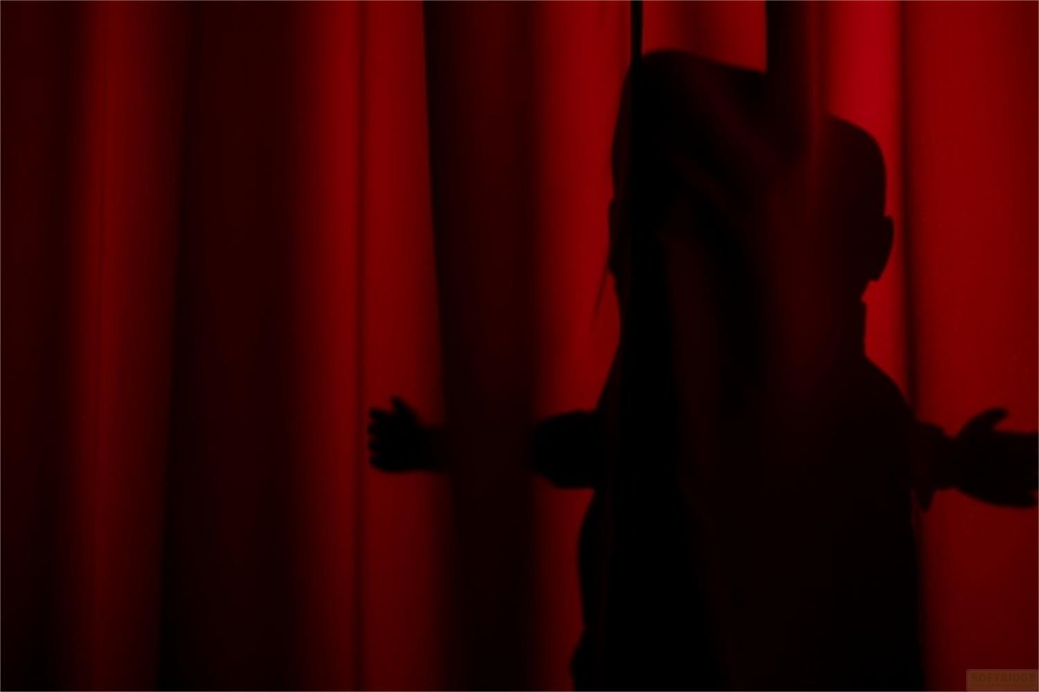 Silhouette di bambini davanti a una tenda rossa, braccia tese.