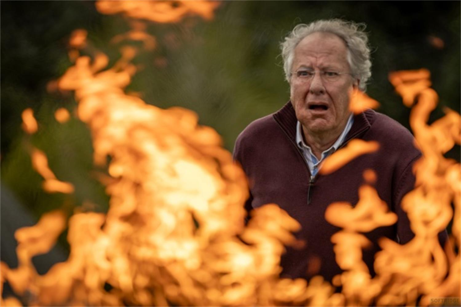 Uomo con espressione scioccata guarda fiamme arancioni brillanti in primo piano.