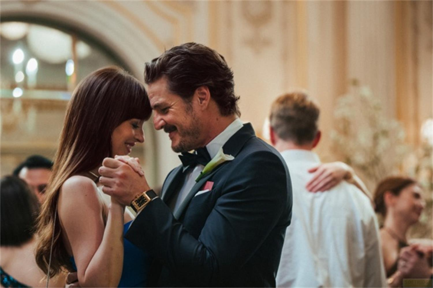 Un uomo in abito e una donna in vestito blu ballano stretti.