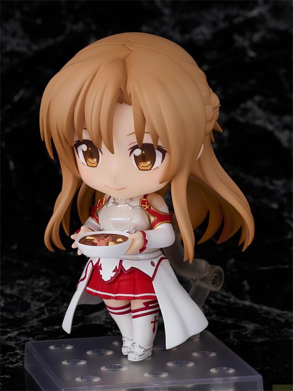 Una figura anime con capelli castani e gonna rossa tiene una ciotola di cibo.
