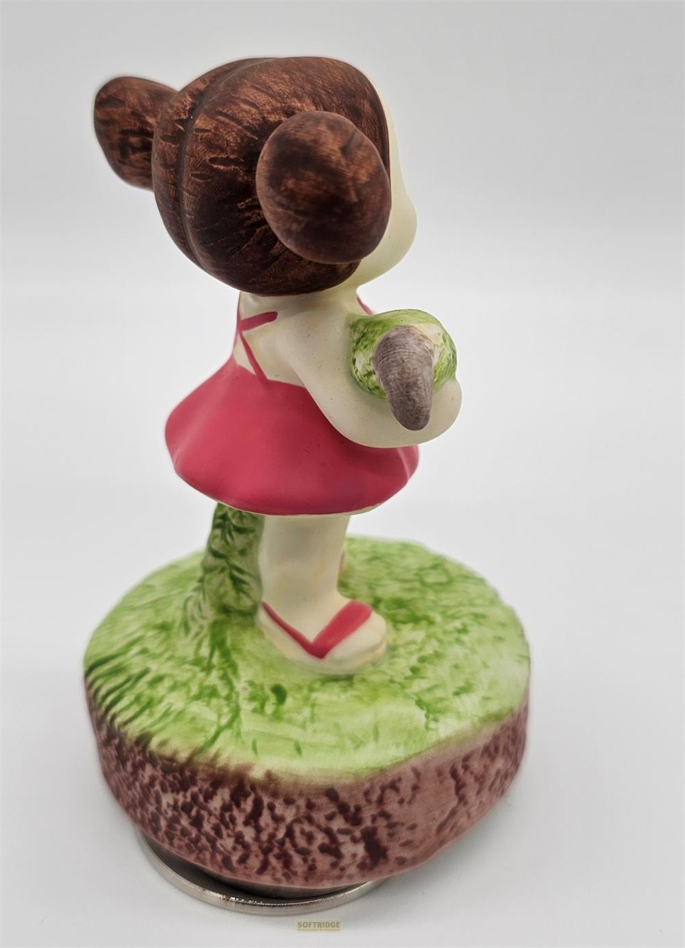 Figur eines Mädchens mit braunen Haaren, das ein rotes Kleid und eine grüne Kugel hält.