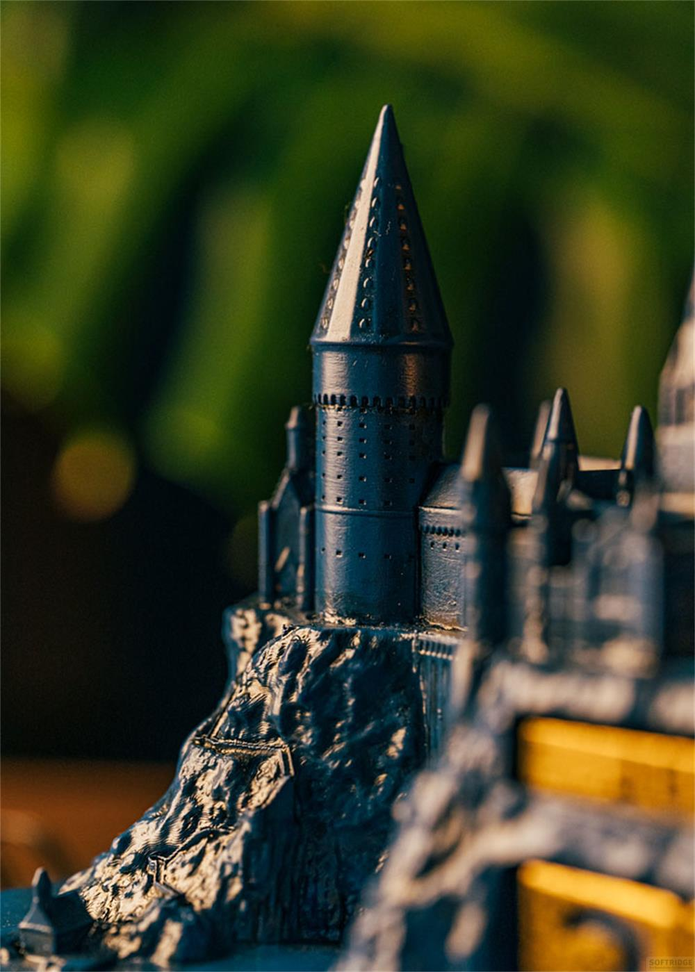Modelo azul oscuro de un castillo con torres puntiagudas sobre base rocosa.