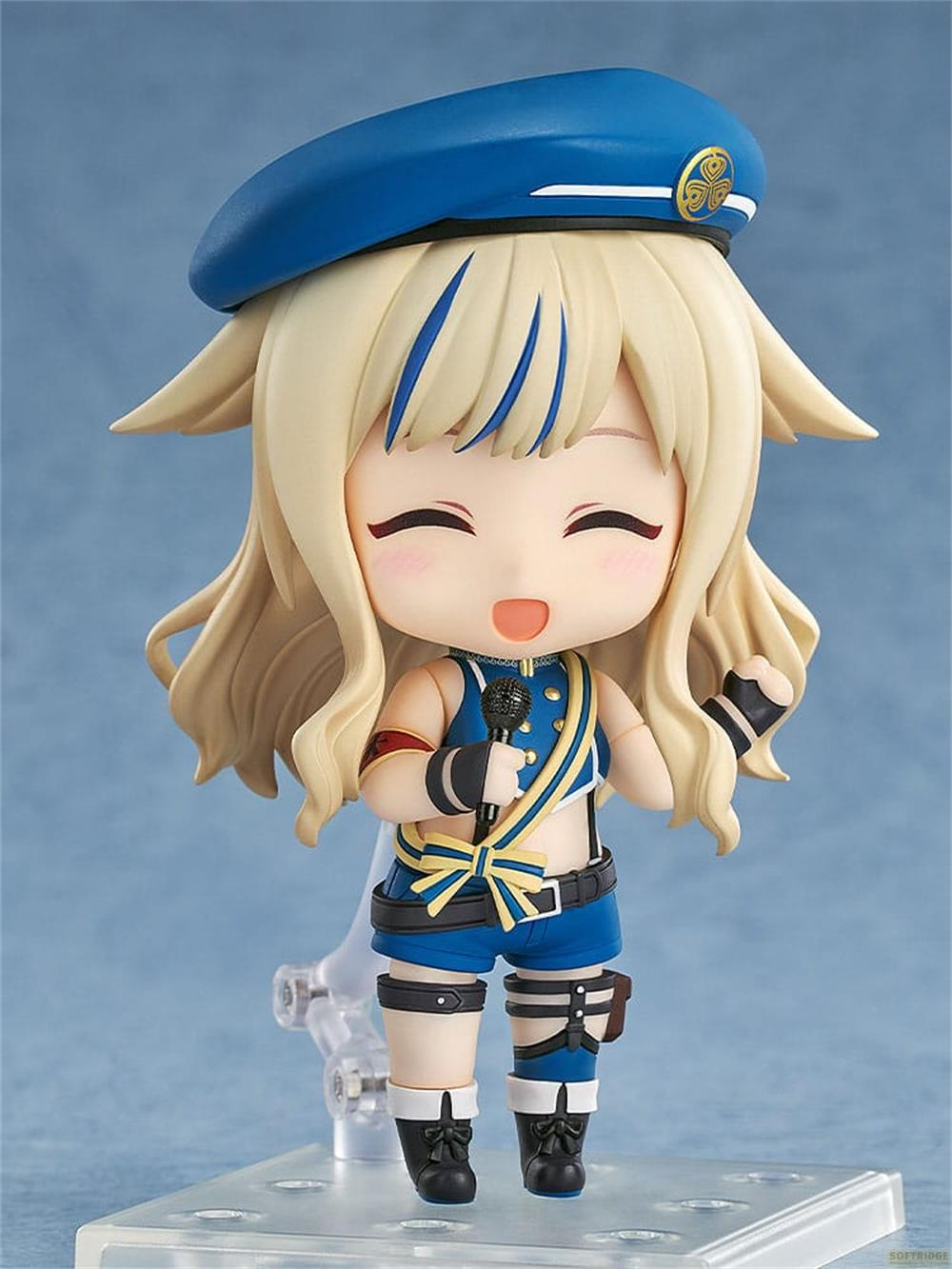 Figura chibi con capelli biondi, berretto blu, che tiene un microfono.