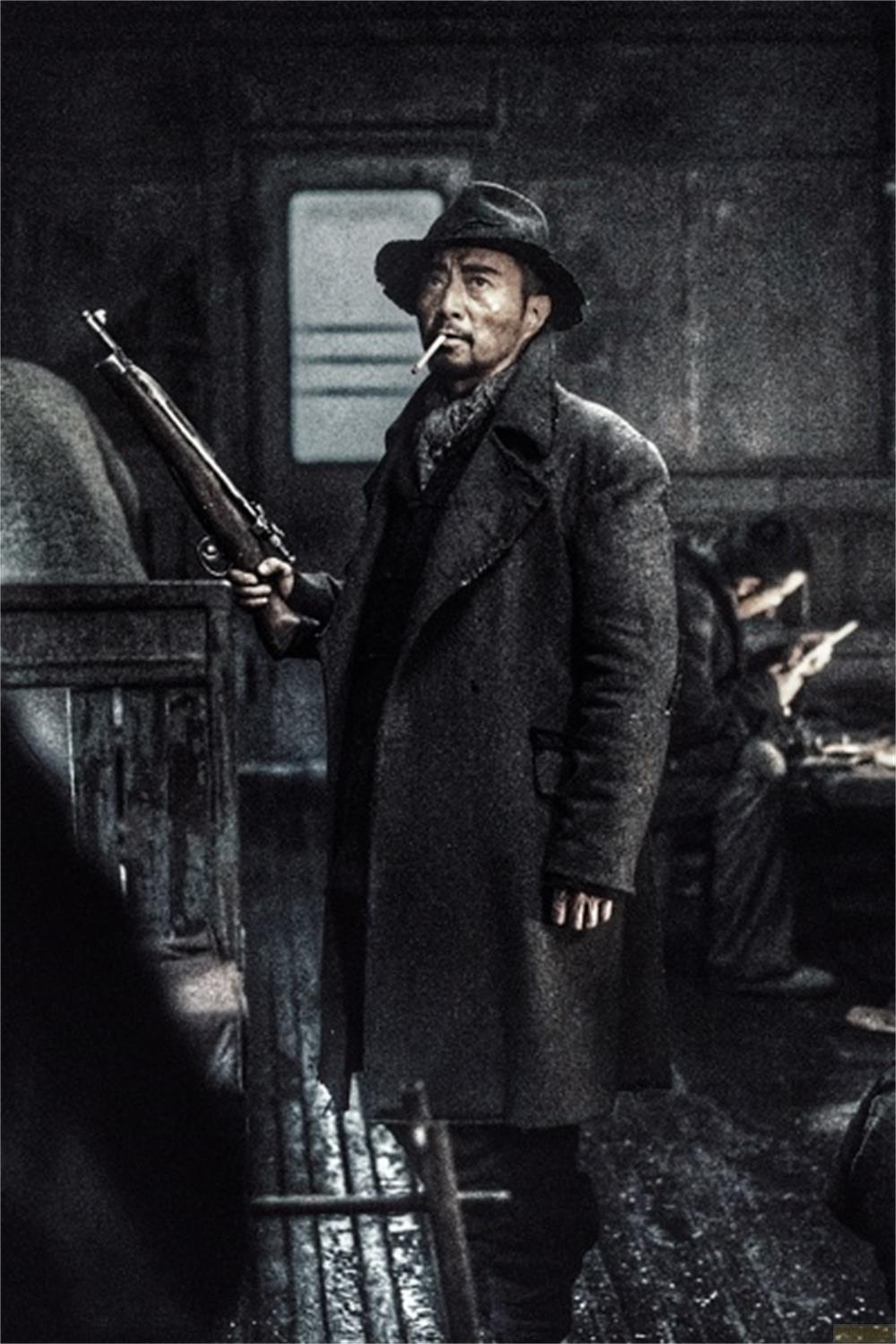 Un uomo con cappello e cappotto tiene un fucile, fumando una sigaretta.