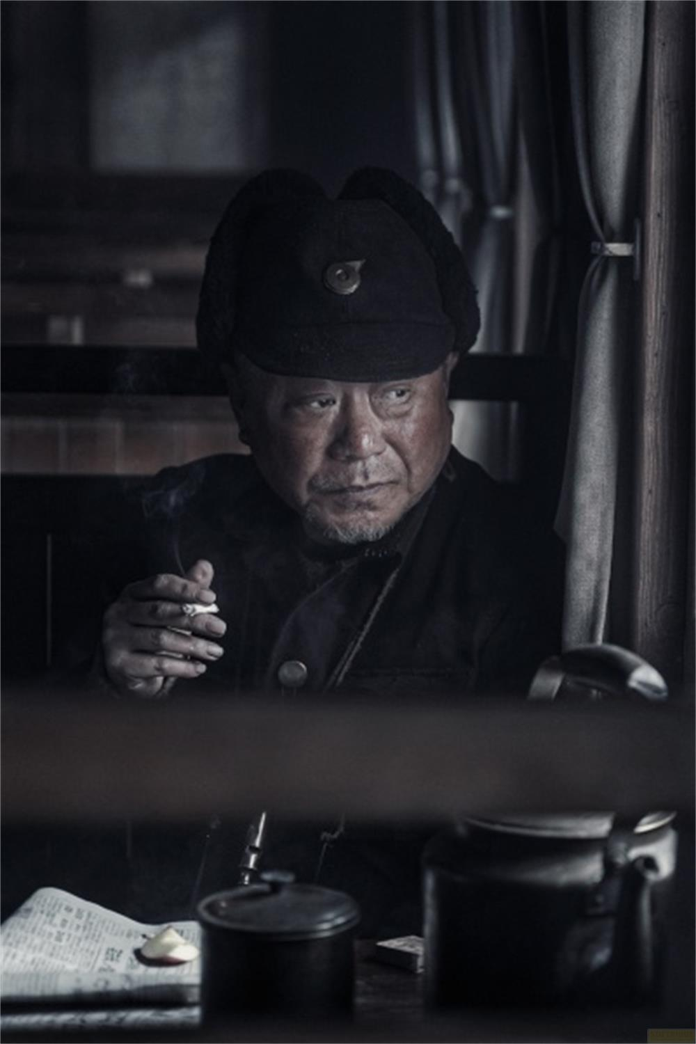 Un uomo con il cappello fuma una sigaretta in una stanza buia.