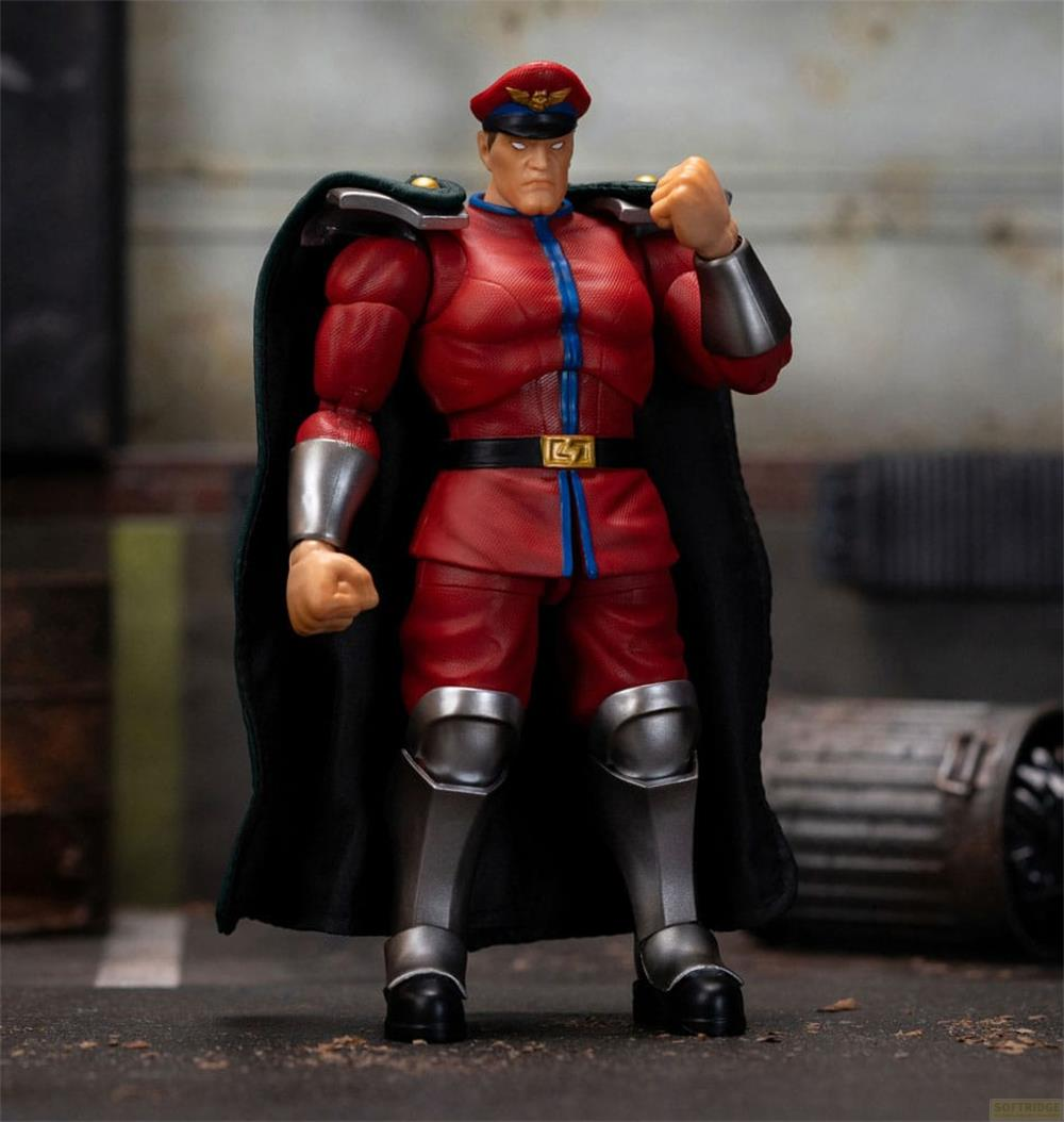 Eine Actionfigur von M. Bison in Rot mit schwarzem Umhang und Hut steht.