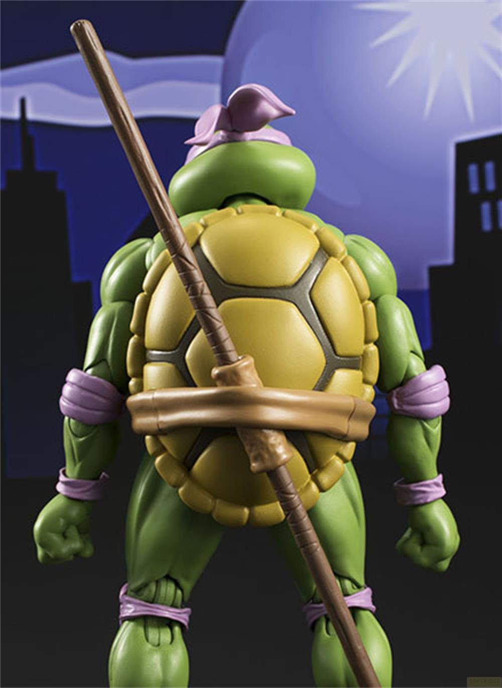 Una figura verde di Tartaruga Ninja Mutante Adolescente con un bastone, vista da dietro.