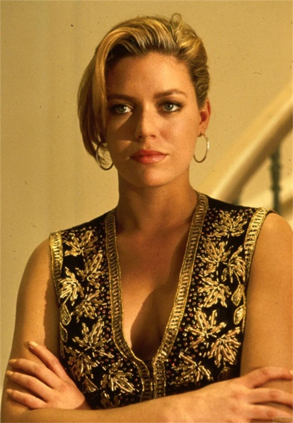 Eine Frau mit blondem Haar trägt eine verzierte Weste mit goldenen Blättern.