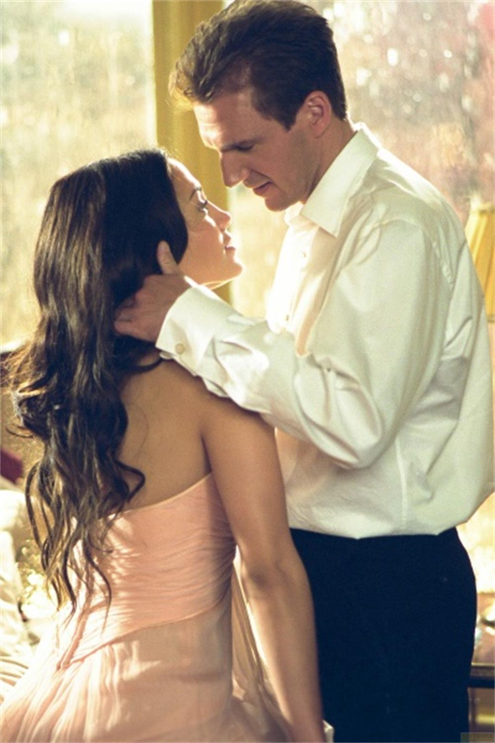Un homme et une femme s'enlacent tendrement. Elle porte une robe rose.