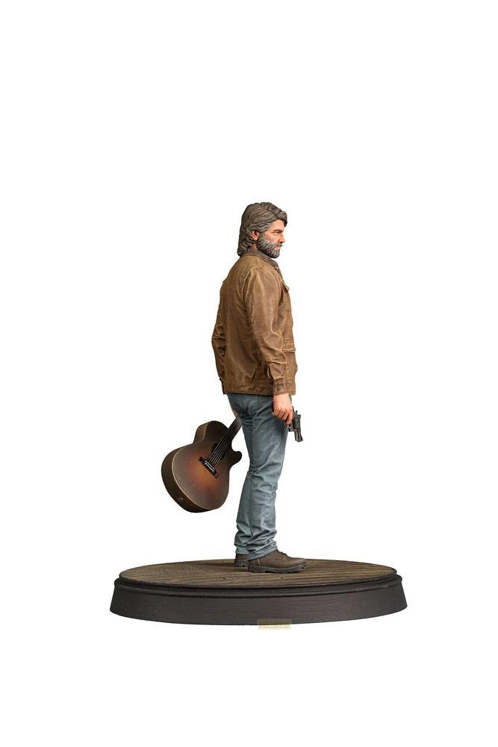 Hombre con barba y chaqueta marrón, sostiene guitarra y pistola en pedestal.