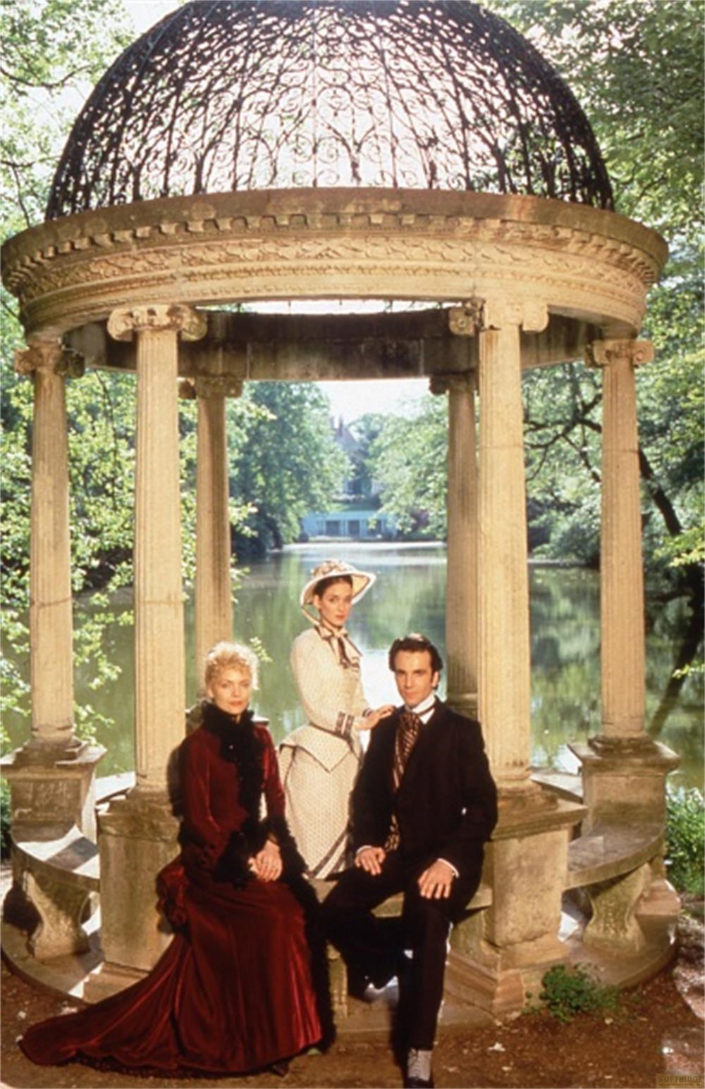 Trois personnes en tenue victorienne posent dans un kiosque au bord de l'eau.