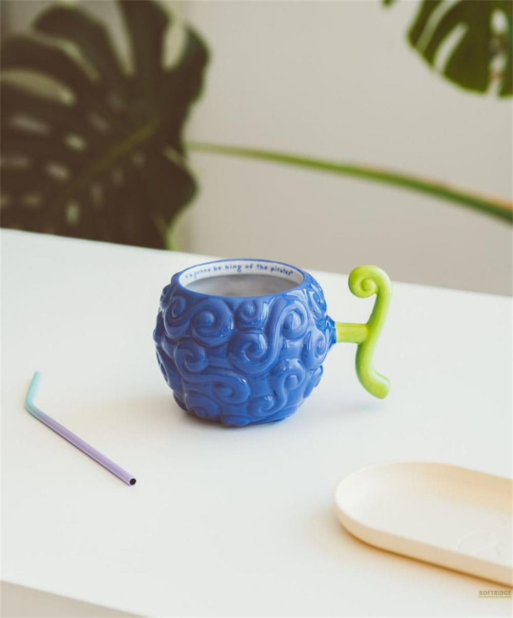Taza azul de fruta del diablo con tallo verde sobre mesa blanca.