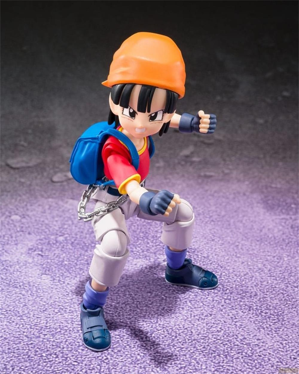 Figura de acción con gorro naranja, mochila azul y camisa roja en pose de lucha.