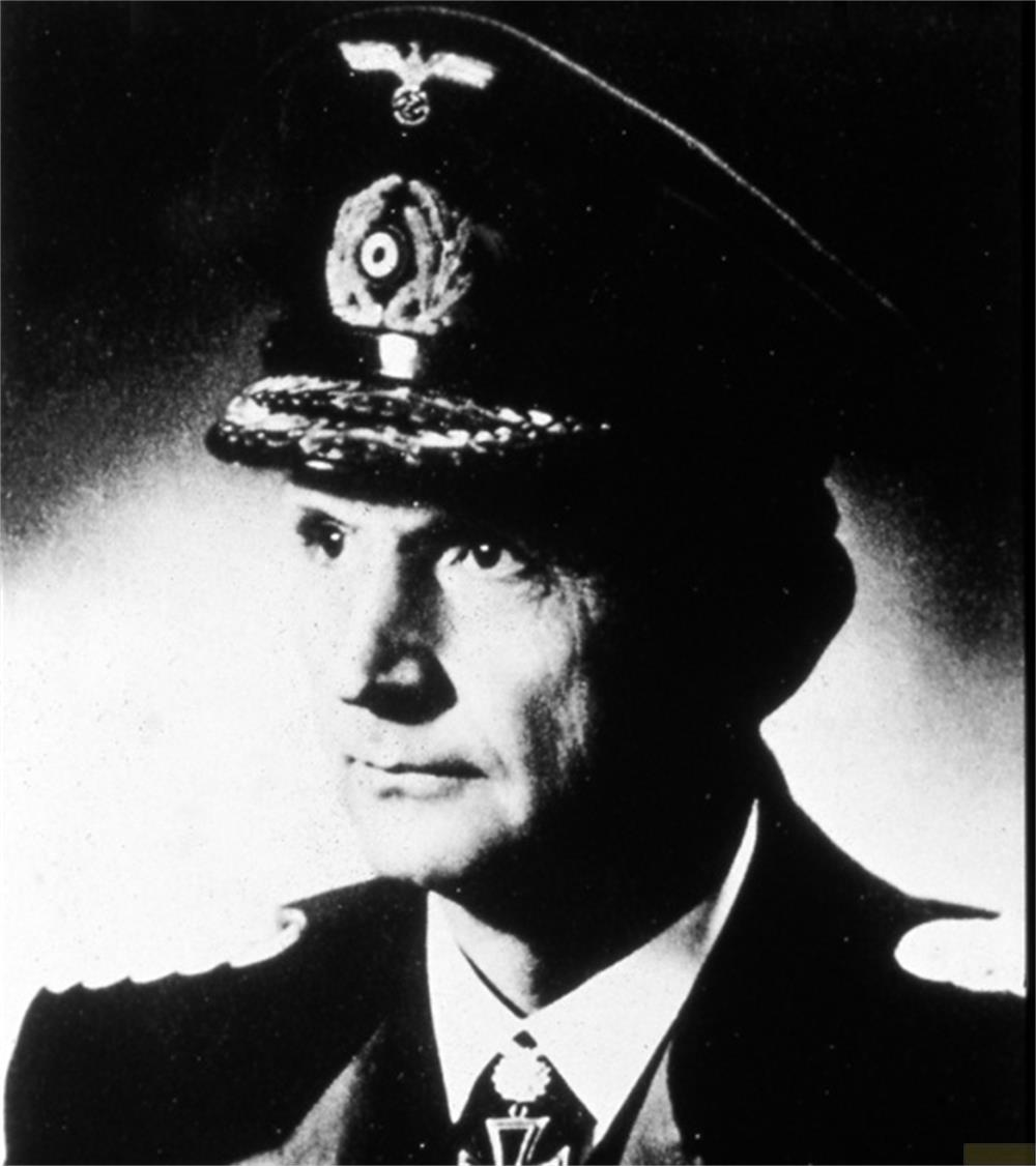 Un uomo in uniforme con cappello e medaglia guarda a sinistra.