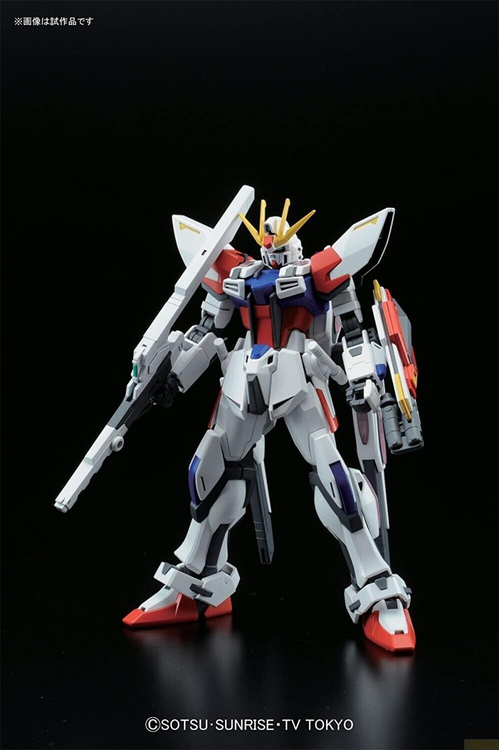 Un robot Gundam blanc, bleu et rouge tenant un fusil et un bouclier sur fond noir.