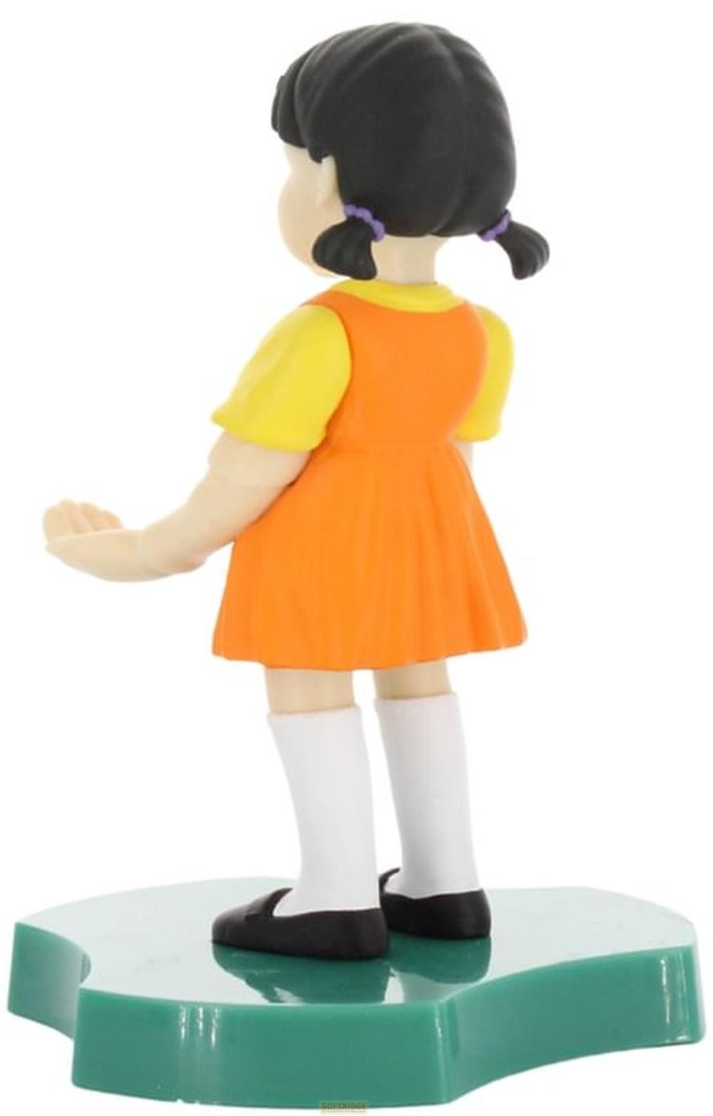 Una figura de una niña con pelo negro, top amarillo y vestido naranja.