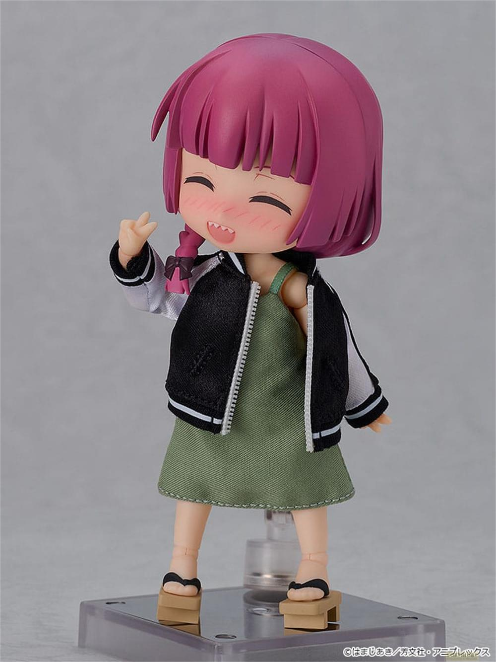 Figura anime con capelli viola, vestito verde, giacca bomber, sorridente.