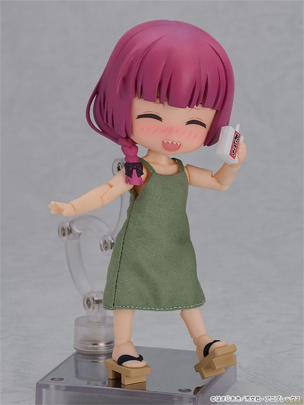 Una figura con capelli viola, vestito verde e zoccoli di legno tiene una bottiglia bianca.