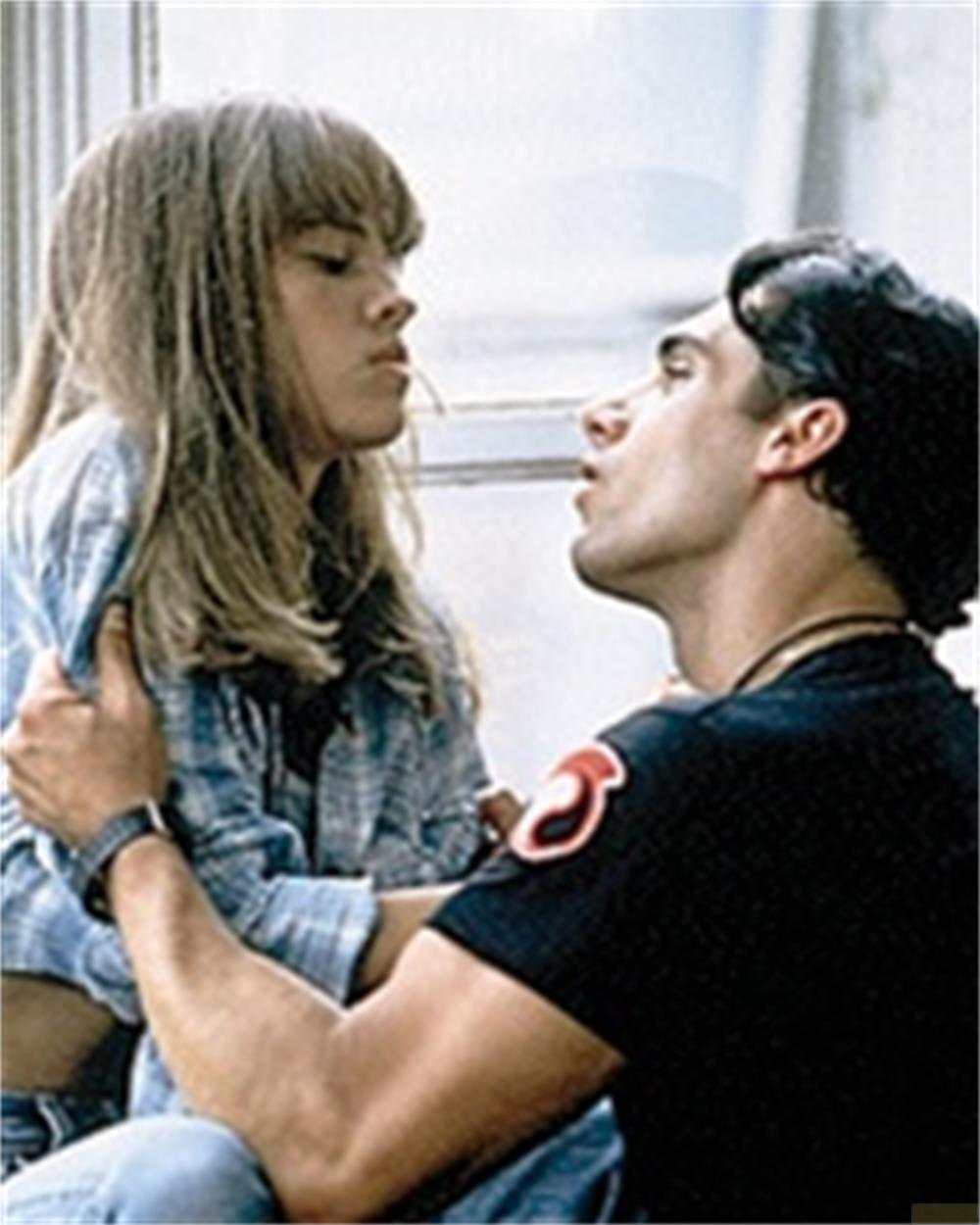 Un homme et une femme se regardent de près, il la tient.
