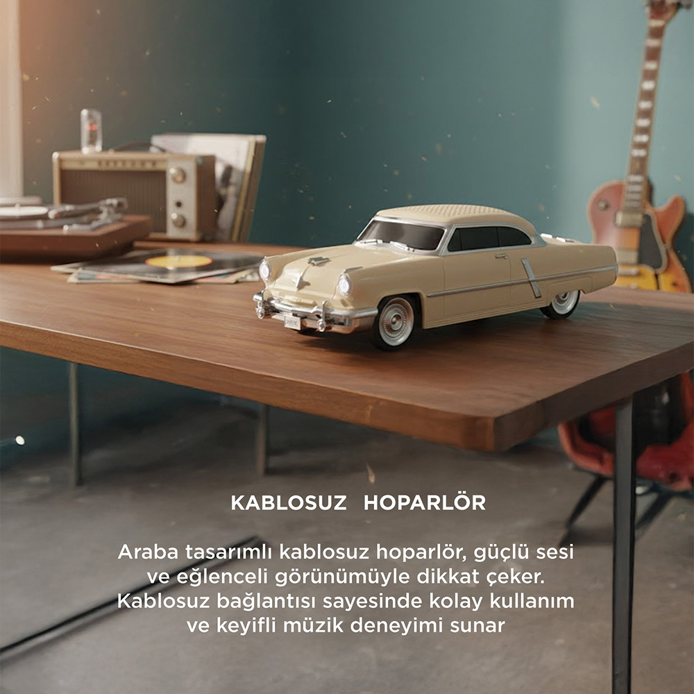 Ahşap masa üzerindeki bej renkli, araba tasarımlı hoparlör, pikap yanında duruyor.
