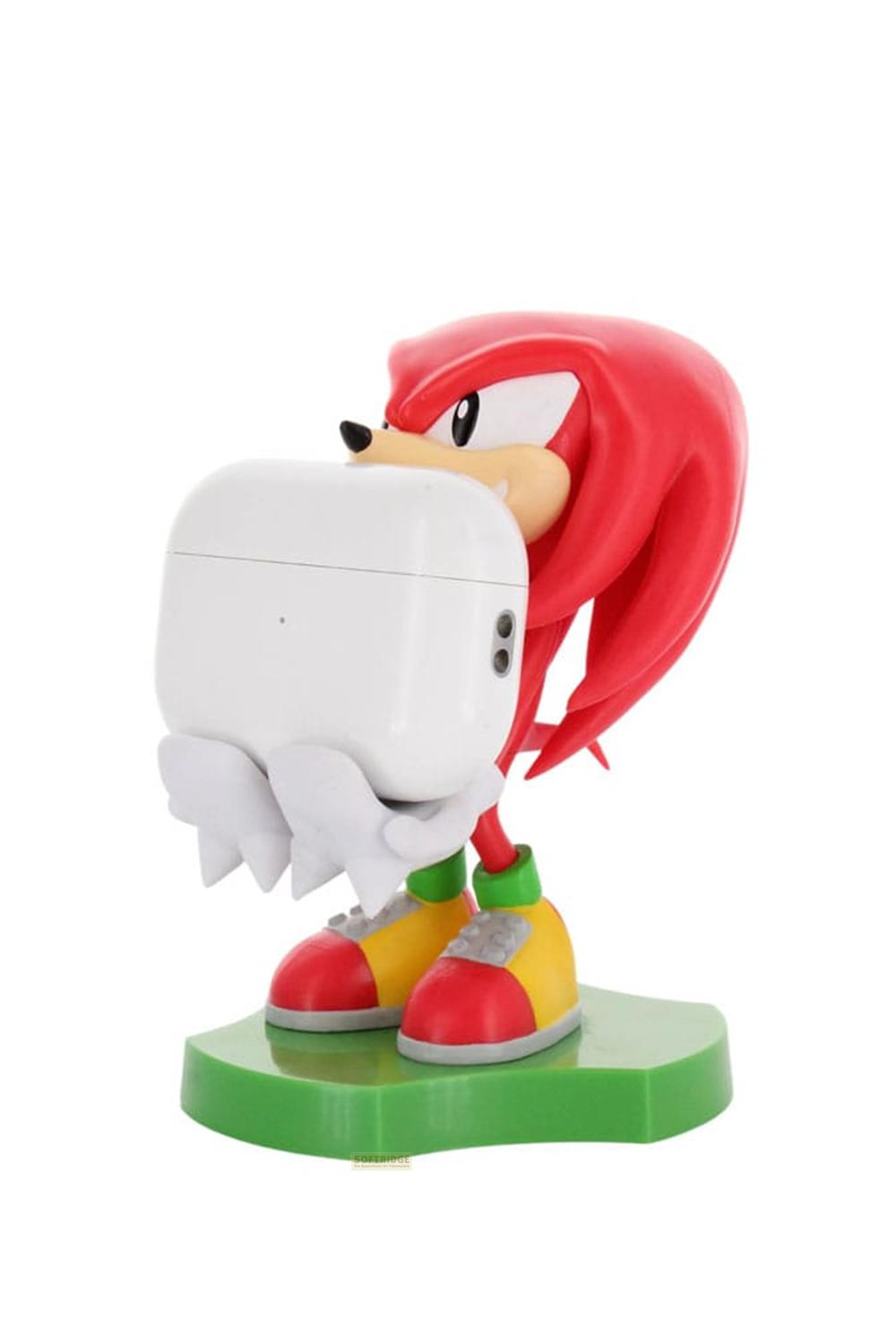 Figurka Knuckles trzymająca białe etui AirPods na zielonej podstawie.