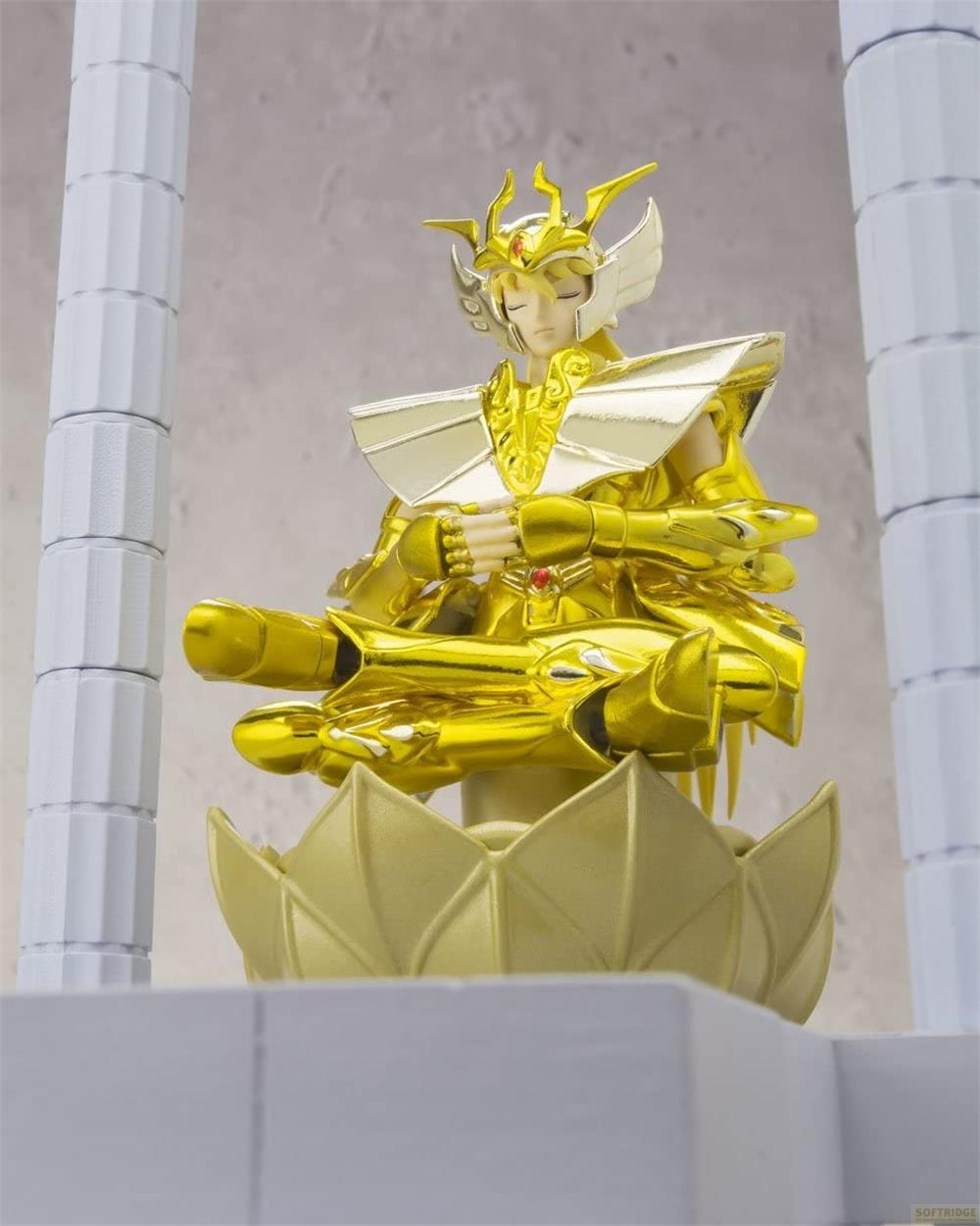 Figura dorata in posa meditativa su base di loto, con colonne sullo sfondo.