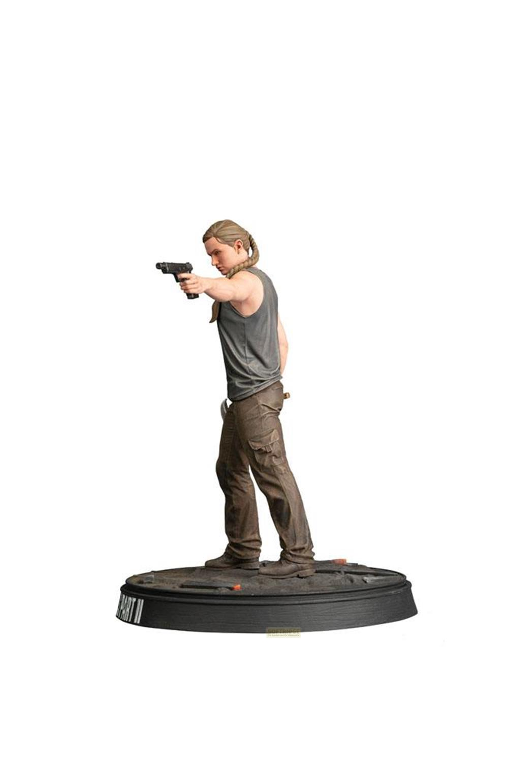 Una figura con pistola en mano, lleva camiseta sin mangas y pantalones cargo, sobre peana.
