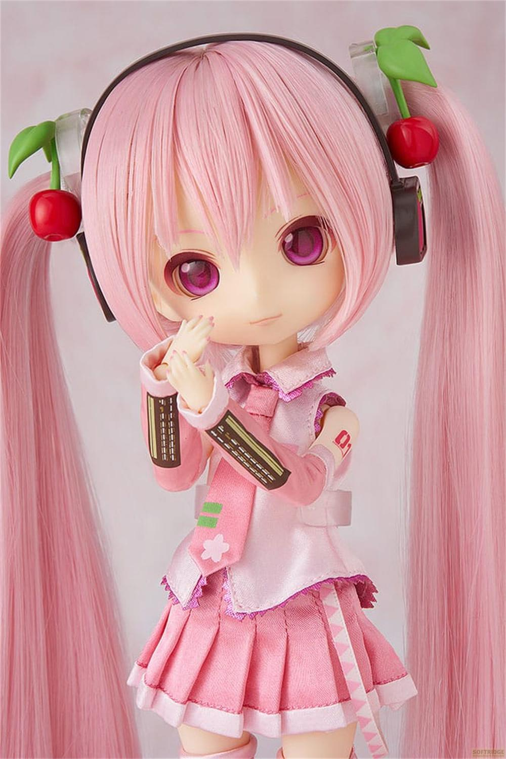 Una figura anime rosa con code gemelle, cuffie e accessori a ciliegia.