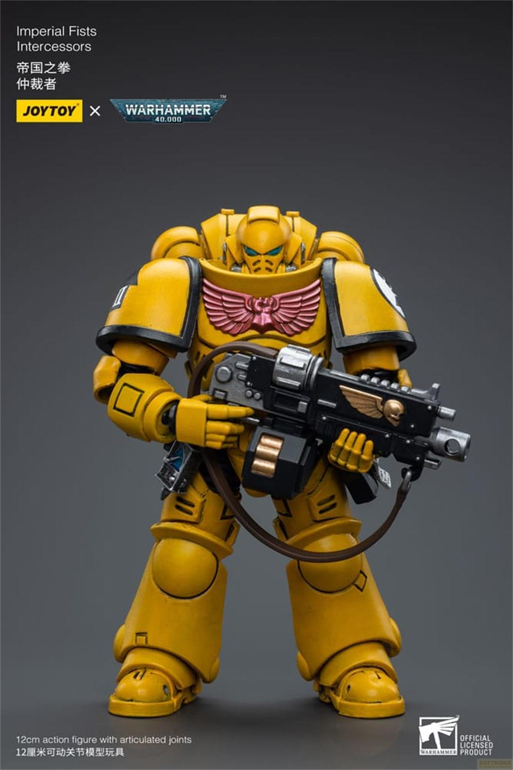 Żółta figurka Space Marine z bronią, herb na piersi, szare tło.