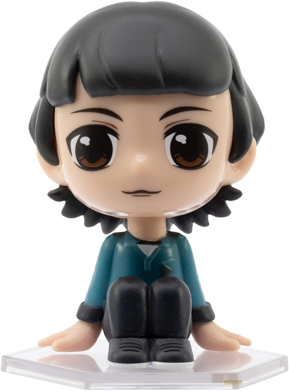 Eine kleine Figur mit schwarzen Haaren und großen Augen sitzt auf einer klaren Basis.