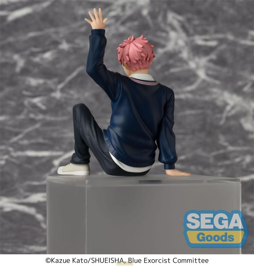 Une figurine aux cheveux roses est assise sur une boîte, levant une main.