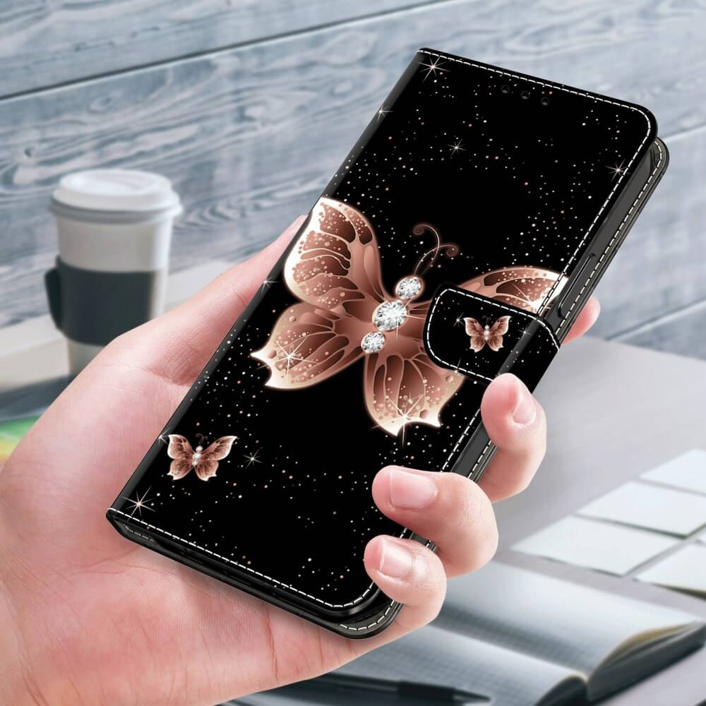 Coque de téléphone noire avec motif papillon et cristaux, tenue en main.