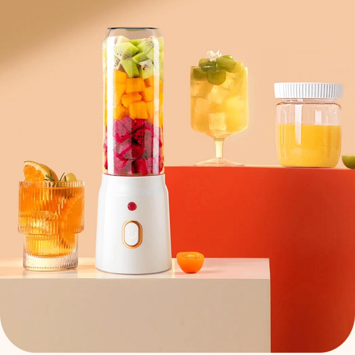 Ein weißer Mixer mit geschichtetem Obst, daneben Getränke in Gläsern.