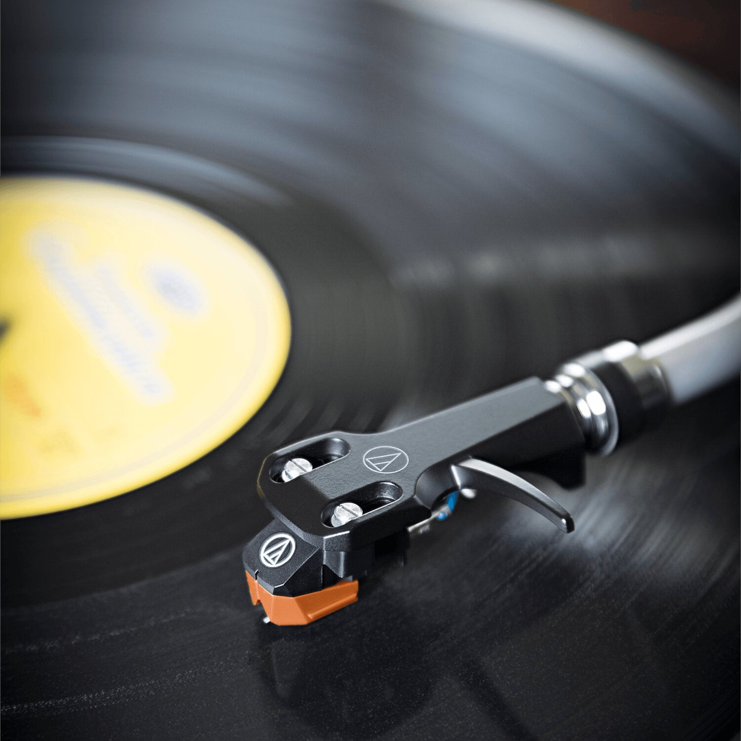 Tonabnehmer auf einer Vinyl-Schallplatte, gelbes Etikett sichtbar.