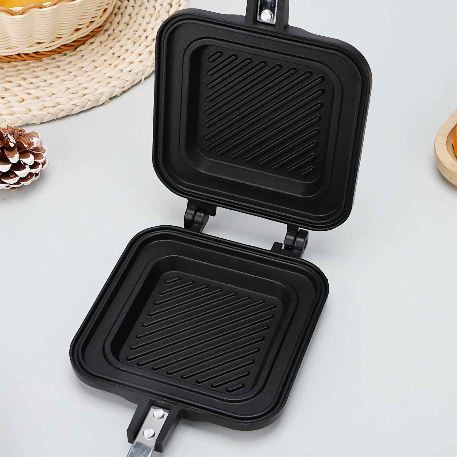 Ein offenes, schwarzes Sandwichgerät mit gerillten Heizplatten und Griffen.