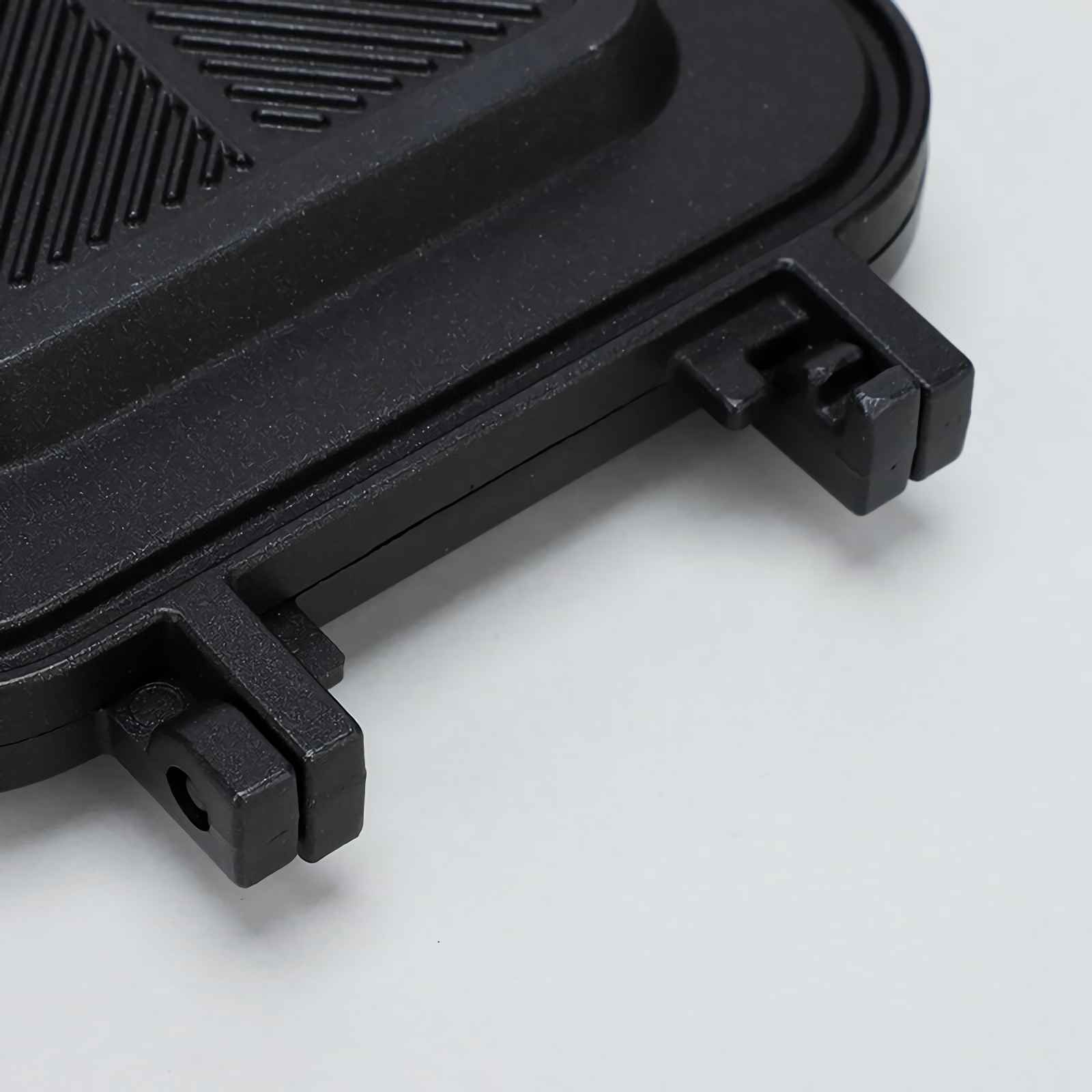 Schwarzer Deckel eines Sandwichmakers mit Rillenmuster und Verriegelungsmechanismus.