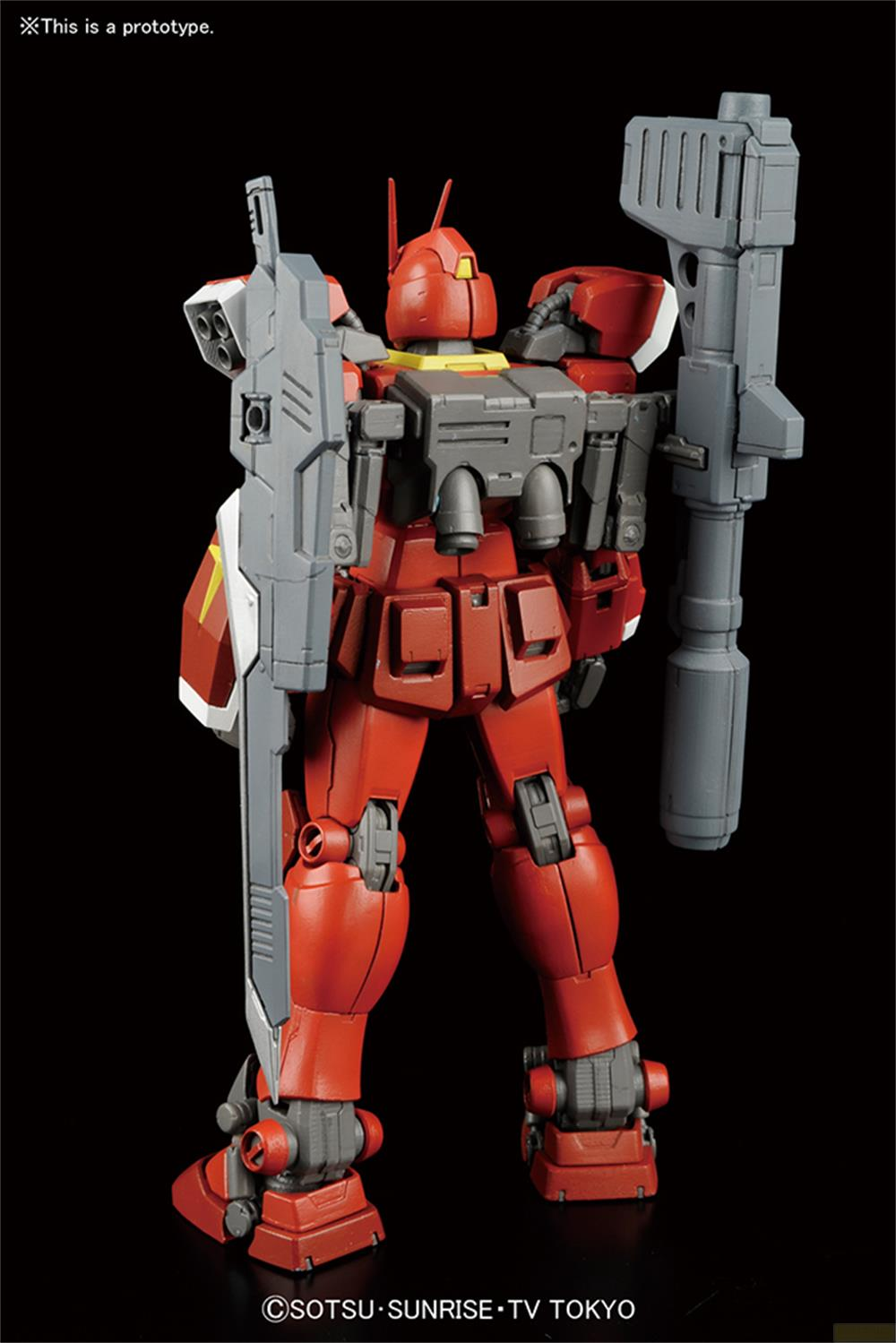 Un robot rouge et gris tenant des armes se dresse sur fond noir.