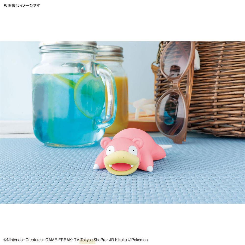 Eine rosa Figur liegt auf einer blauen Matte neben Getränken und Sonnenbrille.