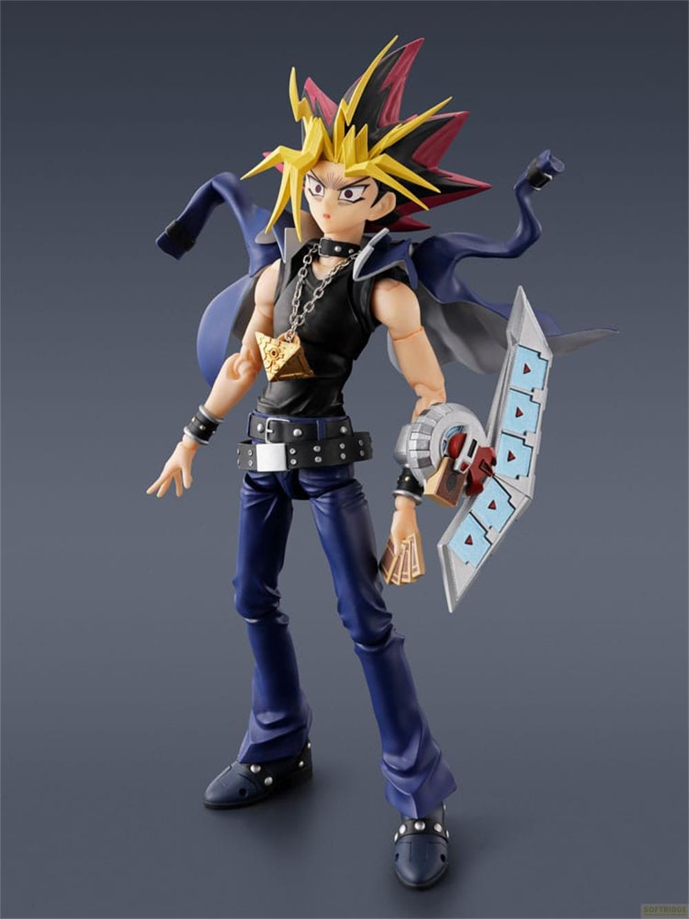 Figur Yugi Muto mit gelben Haaren, schwarzem Shirt, blauer Jacke und Duell-Scheibe.